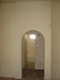 View from the living room to the arched entry-way leading to the bath with two of the bedrooms on either side.